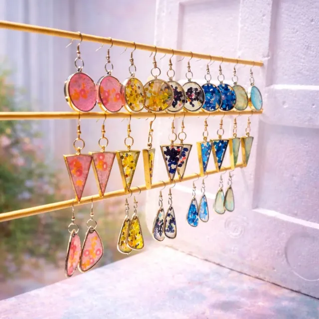 Rows of resin drop earrings on a gold display rail