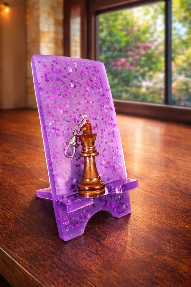 Purple glitter resin phone stand with a chess-king keychain